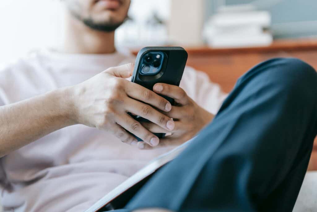 A man sitting on a couch holding a cell phone.